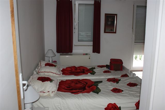 Schlafzimmer mit zwei Betten und Bettwäsche mit Rosen in einem Haus zum Verkauf, Bigovo, Montenegro.