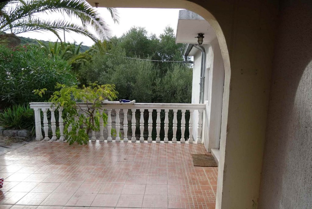 Geräumige Terrasse mit Balustrade und Blick auf den Garten im Haus, Bigovo, Montenegro. Gefliester Boden und mediterranes Grün.