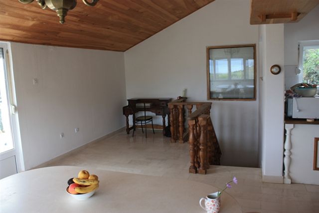 Wohnzimmer in einem Haus in Bigovo, Montenegro: Holzdecke, antiker Tisch, Steinboden und Treppe mit Geländer.
