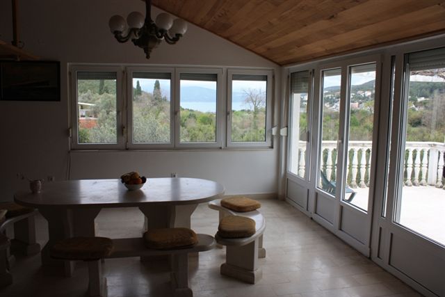 Wohnzimmer mit Steintisch und Meerblick in einem Haus in Bigovo, Montenegro, mit Zugang zur Terrasse mit Balustrade.