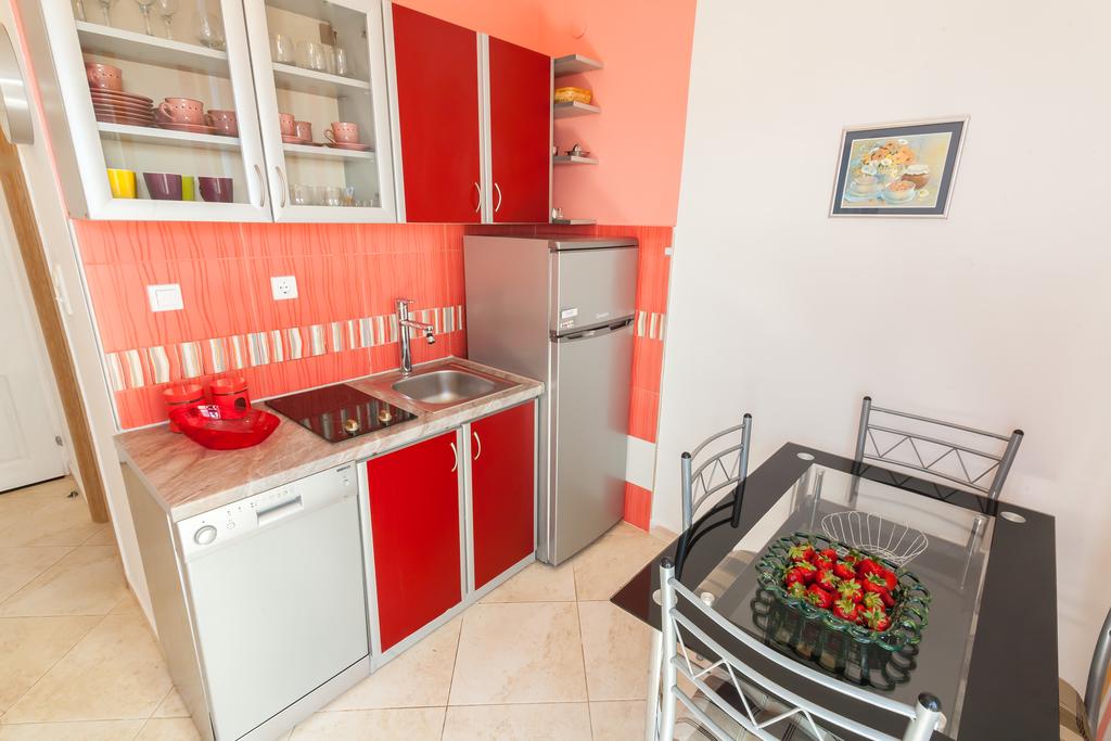 Helle Küche mit roten Fronten, Geräten und Esstisch in einem Haus zum Verkauf in Krimovice, Montenegro.
