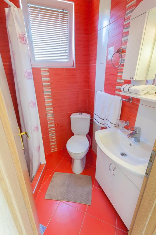Badezimmer mit roten Fliesen, Dusche und weißer Sanitärkeramik in einem Haus zum Verkauf, Krymovica, Montenegro.