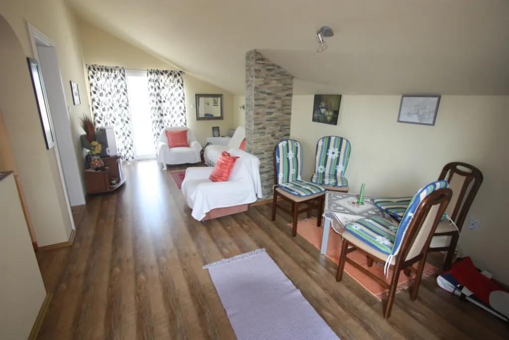 Gemütliches Wohnzimmer in einem Haus in Utjeha, Montenegro: Dachgeschoss, helle Möbel, Steinverkleidung und Essbereich.