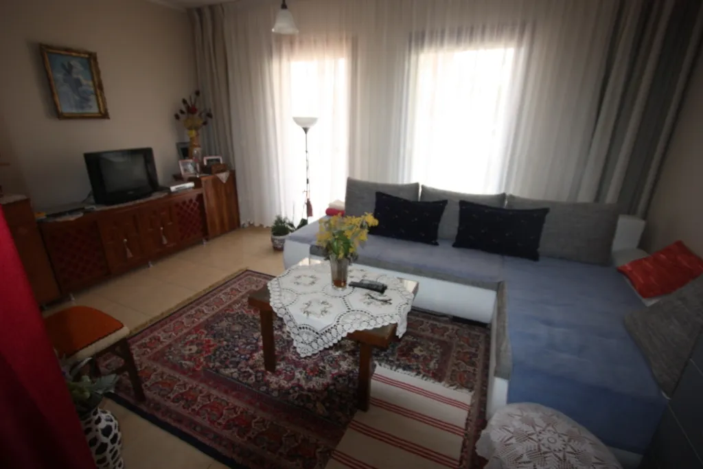 Gemütliches Wohnzimmer mit Ecksofa und Teppich in einem Haus zum Verkauf in Utjeha, Montenegro: Innenraum mit Möbeln und TV.
