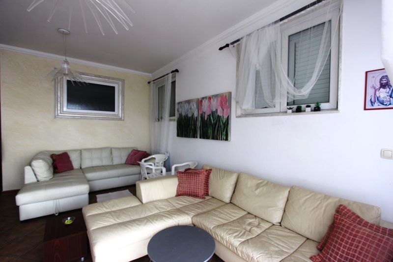 Helles Wohnzimmer mit zwei Ledersofas in einer Wohnung im Ferienort Sveti Stefan, Montenegro. Innenraum mit Gemälden.