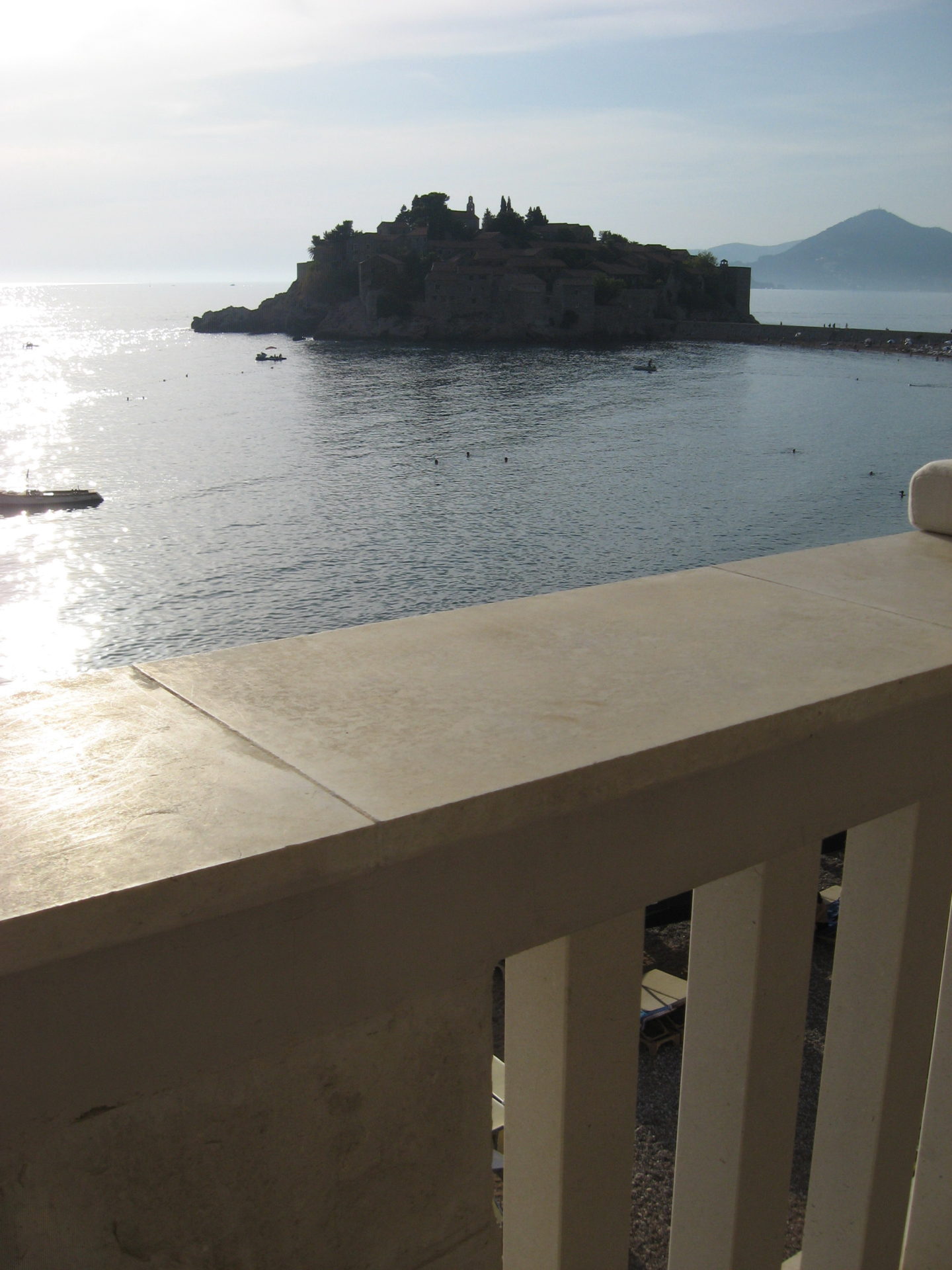 Blick auf die Insel Sveti Stefan in Montenegro vom Balkon der Wohnung mit steinernen Geländern und Meeresblick.
