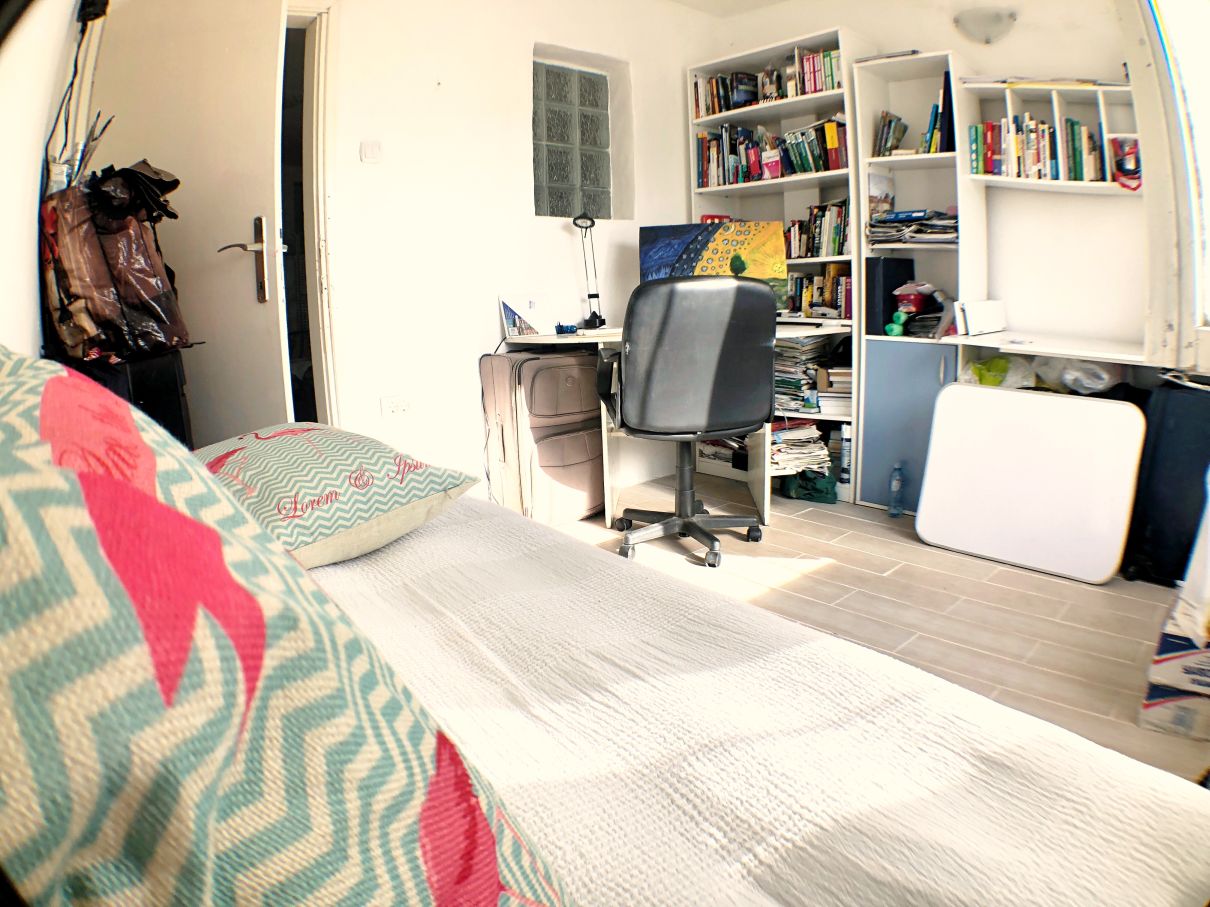Bedroom with a workspace and bookshelves in a house for sale in Risan, Montenegro. Bright interior with a bed.