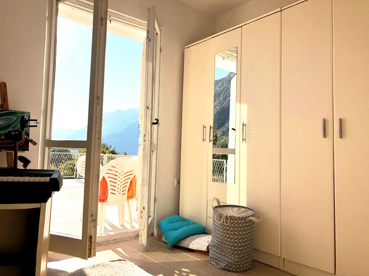 Bedroom in a house in Risan, Montenegro: a bright room with a large wardrobe, access to the terrace, and mountain views.