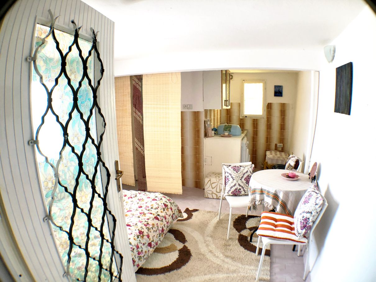 Living room with kitchen in a house in Risan, Montenegro: bed, dining table, rug, and decorative door.