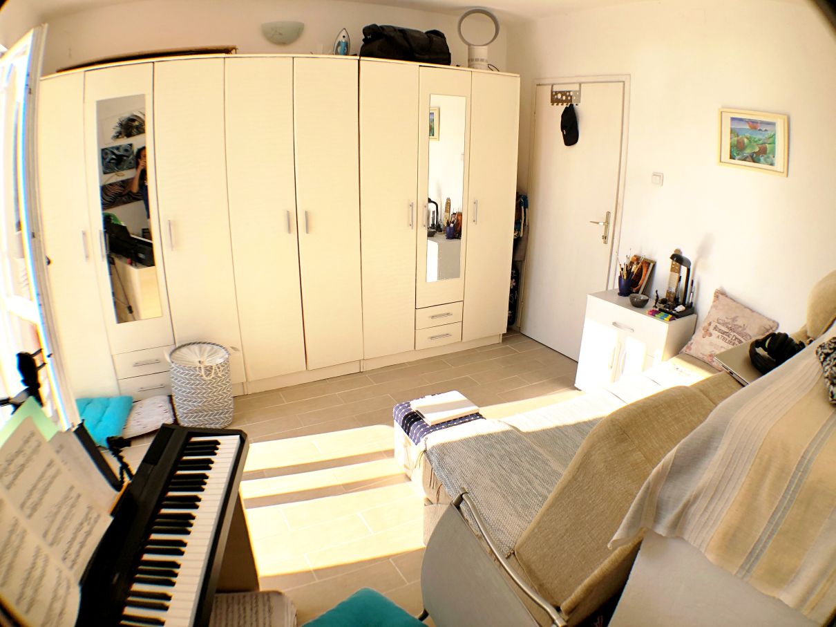 Bedroom in a house in Risan, Montenegro: a bright room with a large white wardrobe, a sofa, and a digital piano.