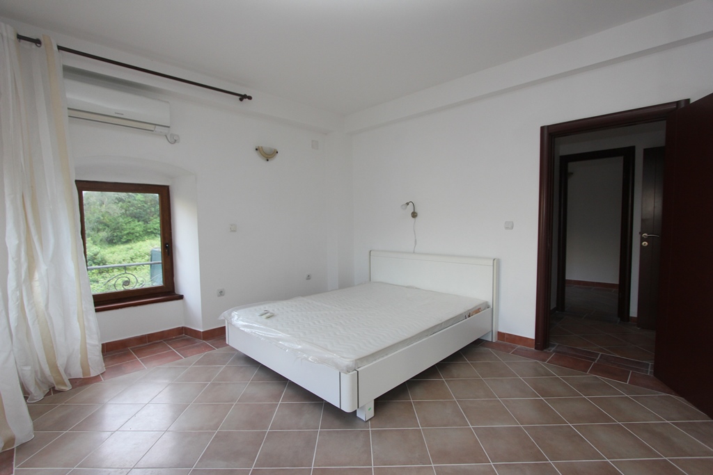 Bright bedroom with a double bed and a view of greenery in a villa, Prčanj, Montenegro. Tiled floor, air conditioning.
