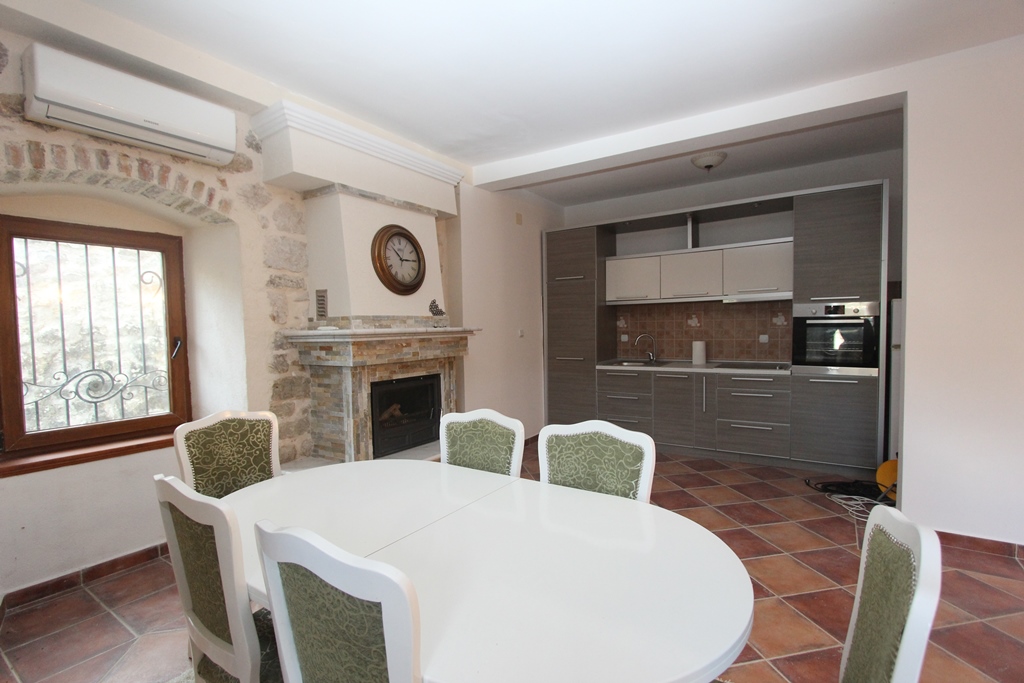 Kitchen-dining room with a fireplace and stone finishes in a villa in Prčanj, Montenegro: modern cabinetry and dining area.