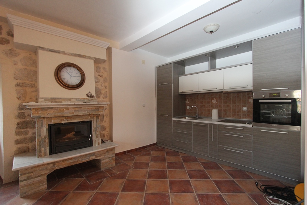 Modern kitchen with a fireplace and stone finishes in a villa in Prčanj, Montenegro: interior with furniture and built-in appliances.