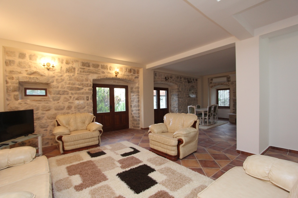 Living room with stone walls and leather furniture in a villa in Prčanj, Montenegro: interior with dining area.