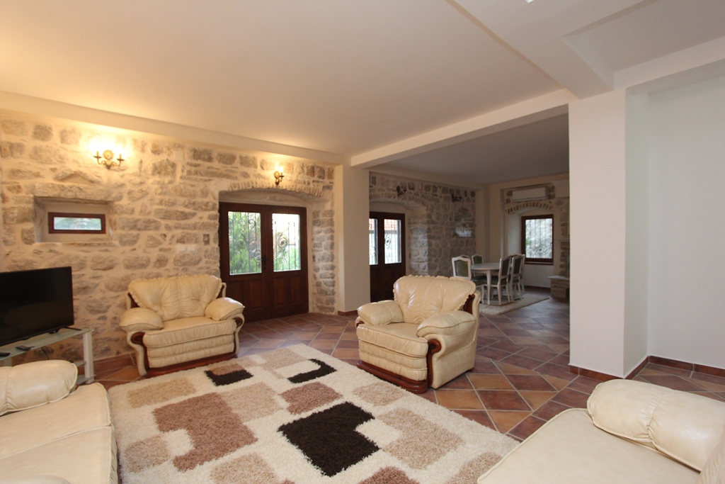 Living room with natural stone finishes in a villa, Prčanj, Montenegro: leather furniture, tiled floor, and dining area.
