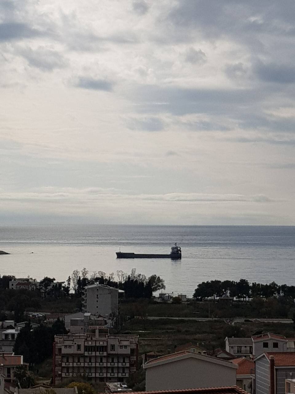 Panoramablick auf das Meer und ein Frachtschiff vom Haus in Šušanj, Montenegro, mit Blick auf die Küstenbebauung und den Strand.