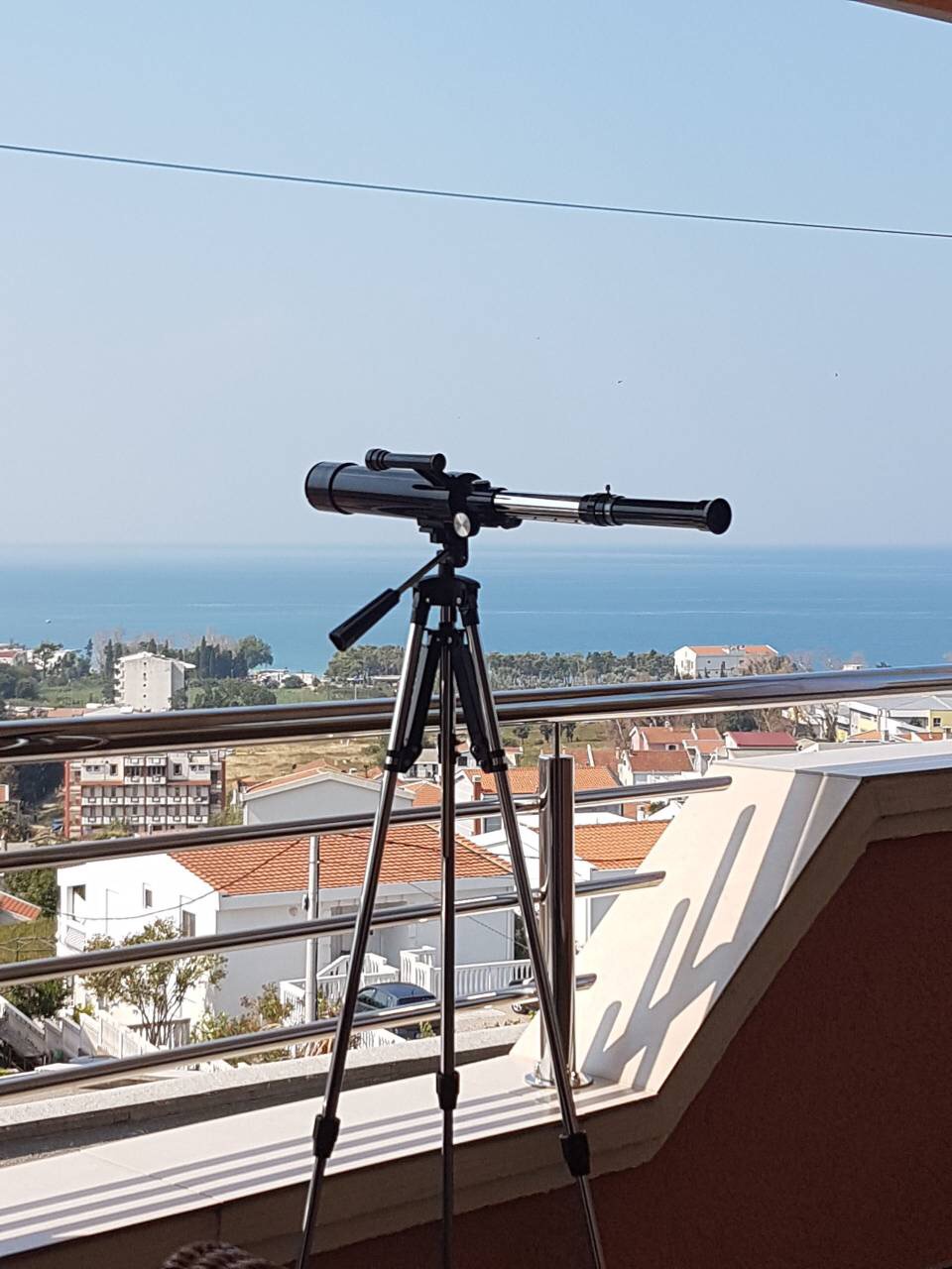 Teleskop auf dem Balkon eines Hauses in Šušanj, Montenegro, mit Panoramablick auf die Adria und die Stadtlandschaft.
