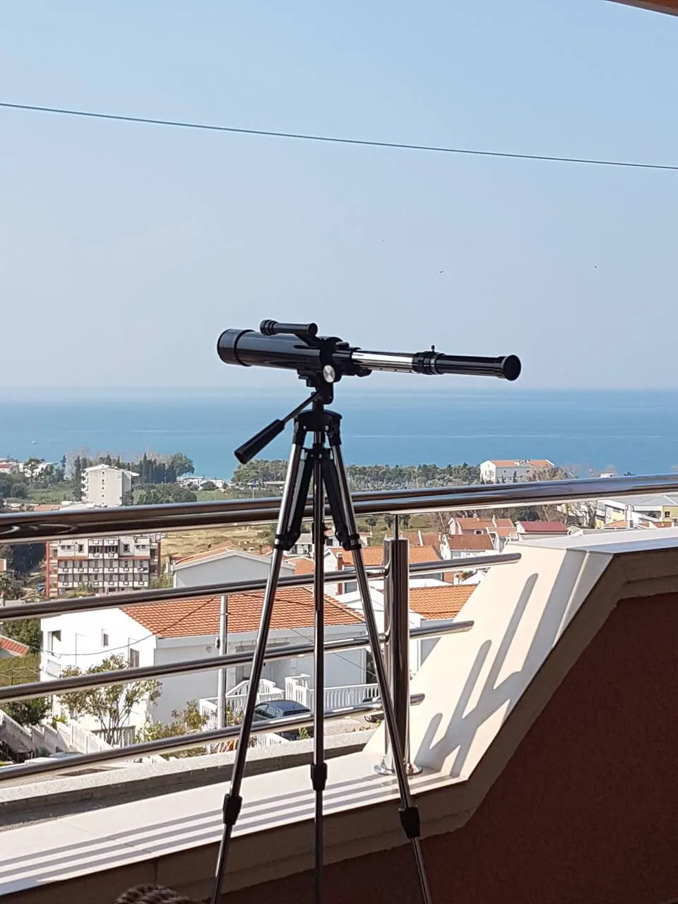 Teleskop auf dem Balkon eines Hauses in Šušanj, Montenegro, mit Panoramablick auf die Adria und die Stadtlandschaft.