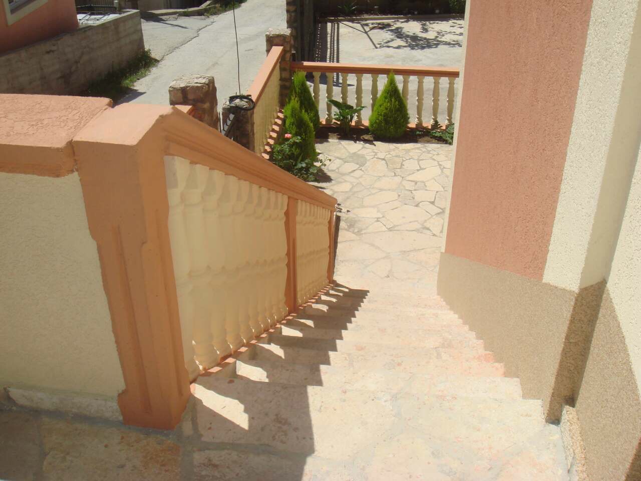 Steintreppe mit Balustrade am Haus in Šušanj, Montenegro, Blick auf die Terrasse und den gepflegten Garten mit Pflanzen.