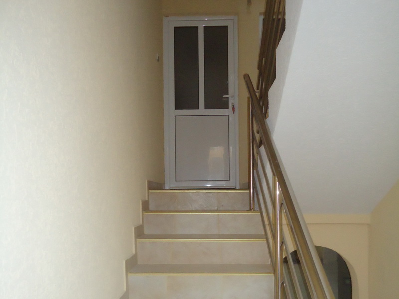 Treppenhaus mit Metallgeländer und heller Verkleidung in einem Haus in Šušanj, Montenegro. Eingangstür zur Wohnung.