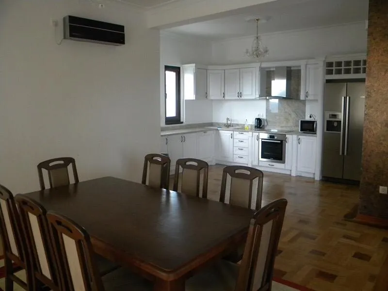 Geräumige Wohnküche mit weißer Einbauküche und Holzesstisch in einer Villa in Herceg Novi, Montenegro.
