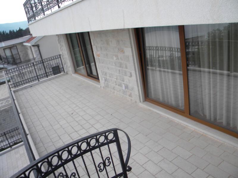 Spacious villa terrace in Herceg Novi, Montenegro, with stone finishes, panoramic windows, and wrought-iron railing.