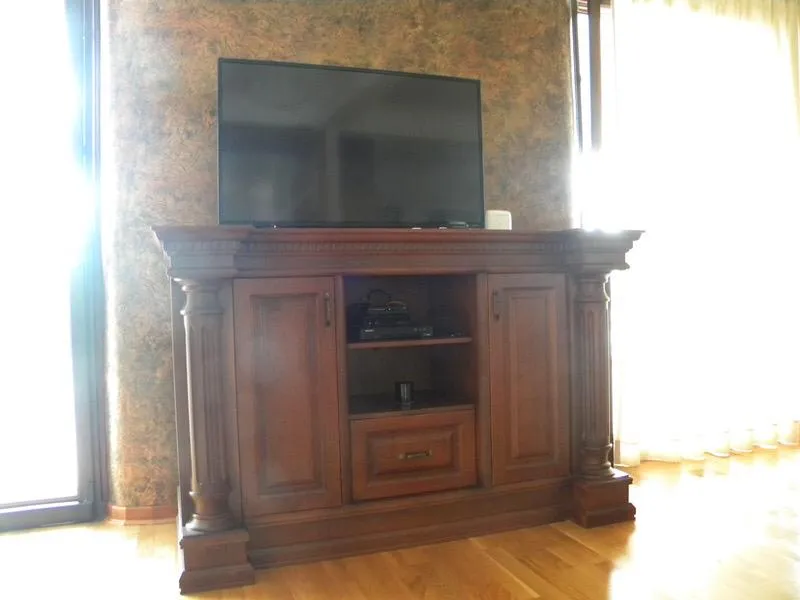 Wohnzimmer in einer Villa in Herceg Novi, Montenegro: klassische TV-Holzkommode vor einer strukturierten Wand.