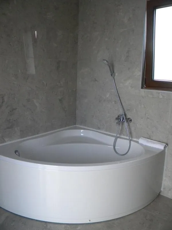 Eckbadewanne in einem modernen Badezimmer mit grauer Steinverkleidung in einer Villa in Herceg Novi, Montenegro.