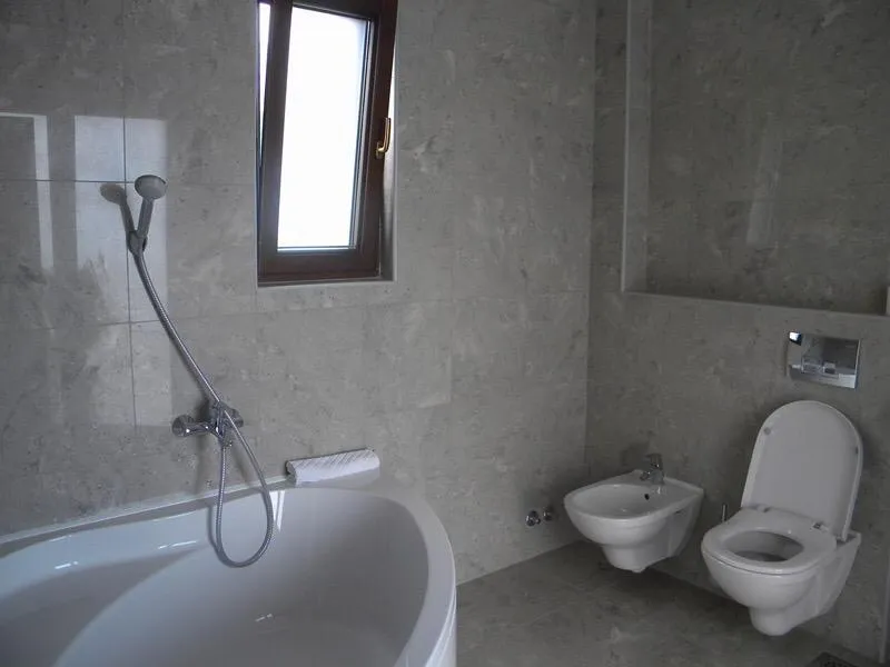 Modernes Badezimmer mit grauer Steinverkleidung, Badewanne und Sanitäranlagen in einer Villa in Herceg Novi, Montenegro.
