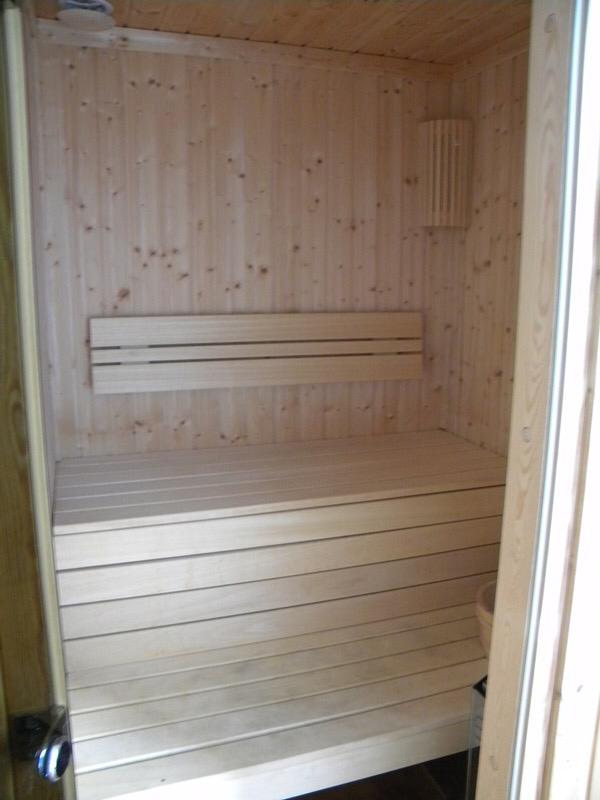 Interior of a modern wooden sauna in a villa in Herceg Novi, Montenegro: light wood finish, benches, and lighting.