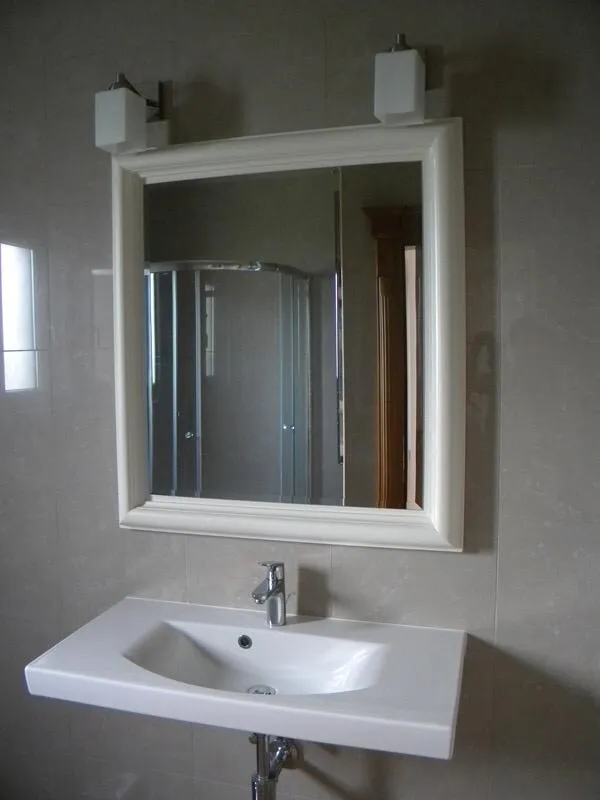 Modernes Badezimmer in einer Villa, Herceg Novi, Montenegro: weißes Waschbecken, Spiegel mit Rahmen und Duschkabine.