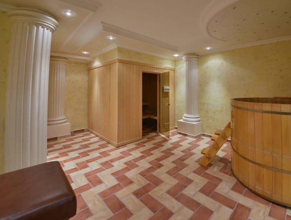 Spa area with a sauna and wooden plunge tub in a villa in Herceg Novi, Montenegro: interior with columns and tiled floor.