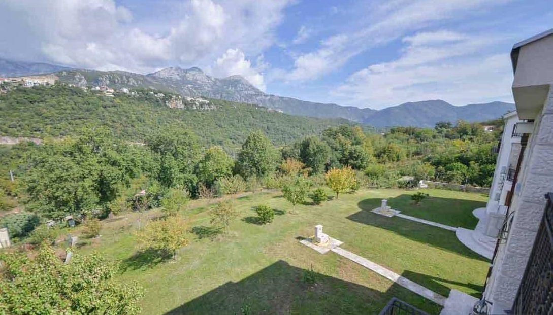 View from the villa terrace in Herceg Novi, Montenegro: a green garden, a well-kept lawn, and panoramic mountain views.
