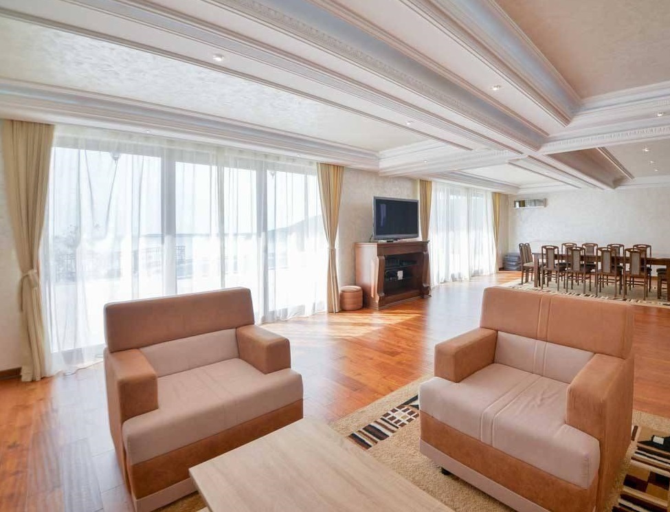 Spacious living room with panoramic windows in a villa, Herceg Novi, Montenegro: soft seating, dining area, and decor.
