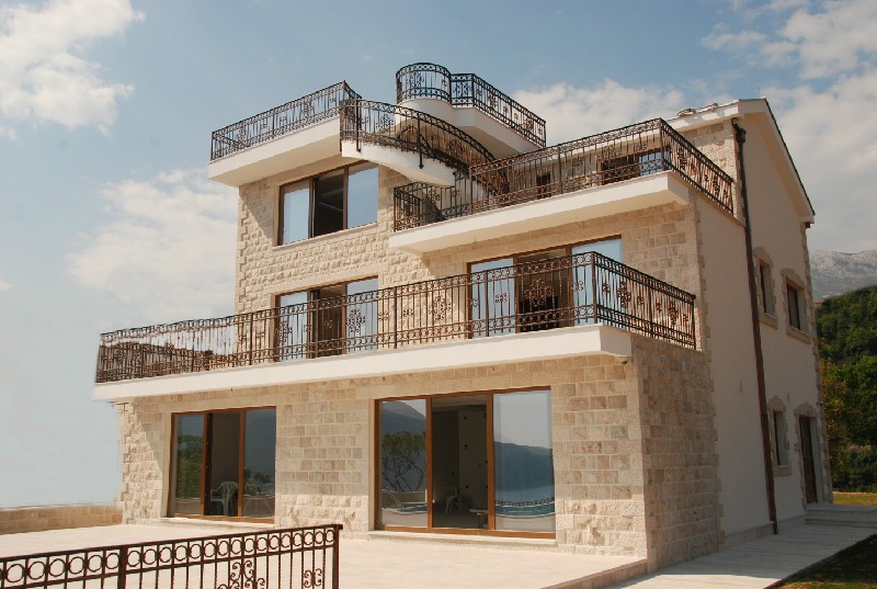 Three-story stone villa with terraces and wrought-iron railings in Herceg Novi, Montenegro. Front view of the house.
