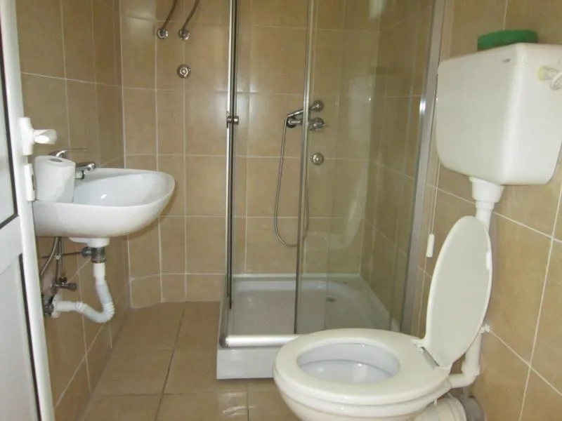 Badezimmer in einem Haus in Kotor, Montenegro: Duschkabine, weiße Sanitärkeramik und beige Wandfliesen.
