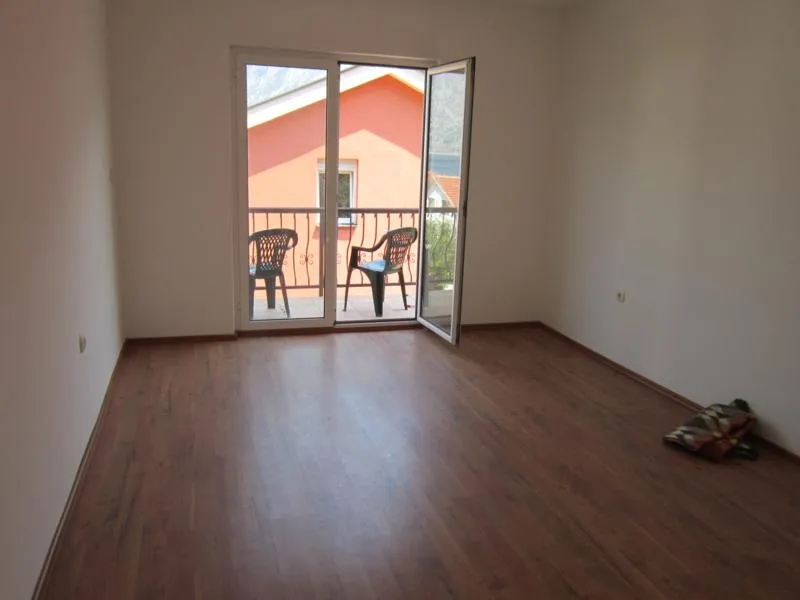Helles Wohnzimmer mit Laminat und Zugang zum Balkon in einem Haus, Stadt Kotor, Montenegro.