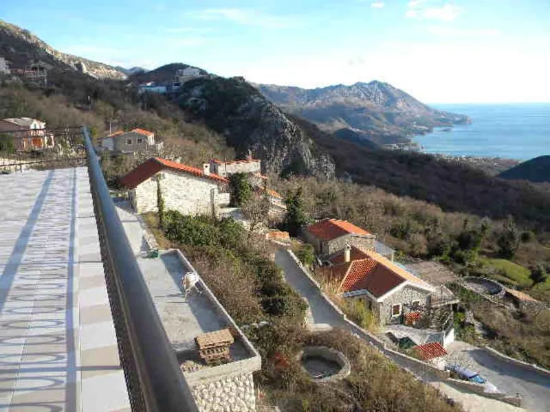Široki kadar balkona sa pogledom na živopisni pejzaž sa planinama i morem.