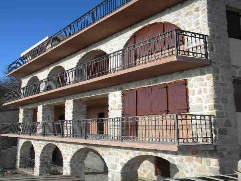 Dreistöckiges Haus im mediterranen Stil mit Steinverkleidung und schmiedeeisernen Balkonen in Budva, Montenegro.