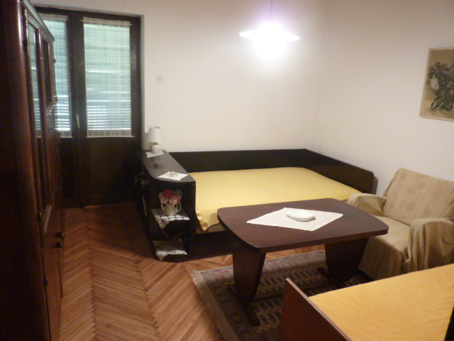 Wohnzimmer in einem Haus in Kumbor, Montenegro: Parkettboden, dunkle Holzmöbel, Sofa und Esstisch.