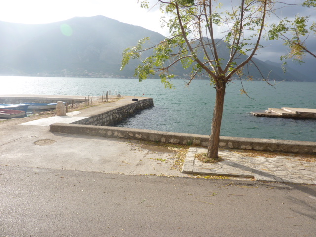 Meerblick und privater Steg am Haus in Kumbor, Montenegro: Uferpromenade mit Baum und Berglandschaft im Hintergrund.