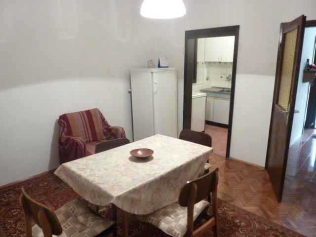 Wohnzimmer mit Essbereich im Haus, Kumbor, Montenegro: Holzboden, Tisch, Stühle und Blick auf die Küche.