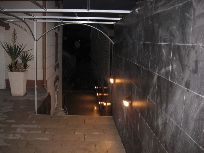 Abendterrasse eines Hauses in Tivat, Montenegro, mit dekorativer Wandbeleuchtung und Bodenfliesen im modernen Stil.