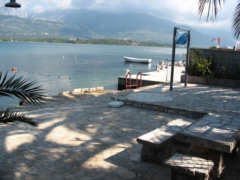 Terrasse mit Steintisch am Meer in Tivat, Montenegro: privater Zugang zum Wasser, Steg und Bergblick.