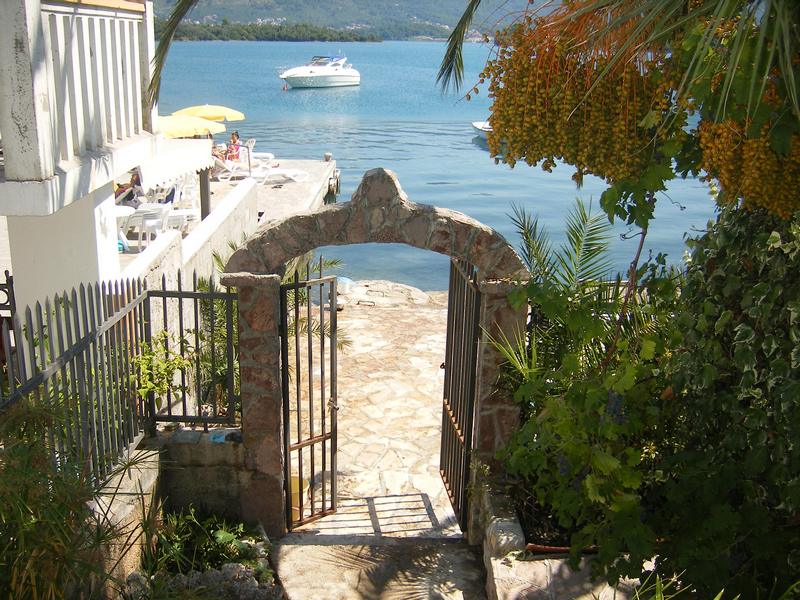 Steinbogen mit Zugang zum Meer und privatem Steg am Haus in Tivat, Montenegro, Blick auf eine Yacht und die Bucht.