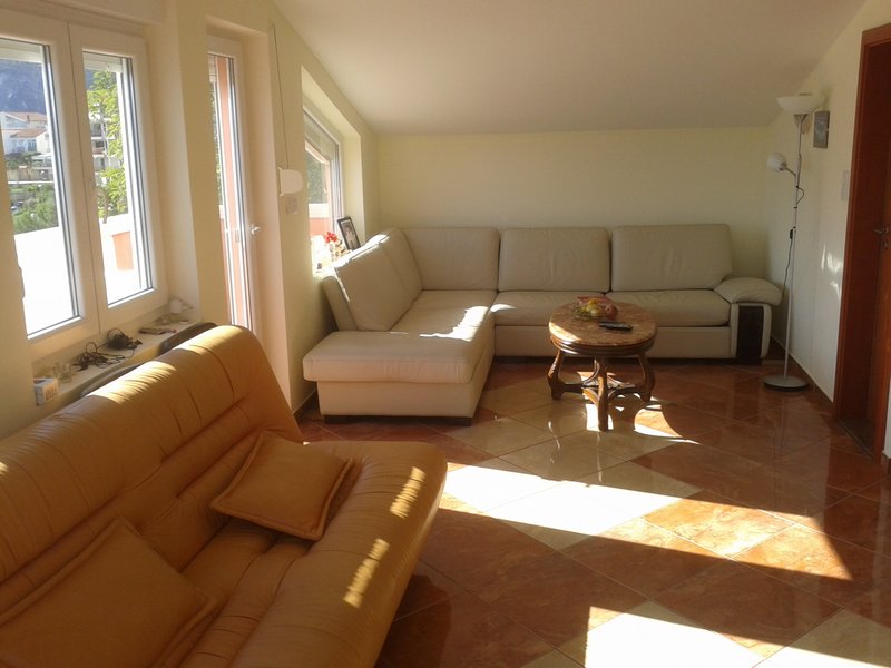 Helles Wohnzimmer mit Ledersofas und Fliesenboden in einer Wohnung in Igalo, Montenegro.