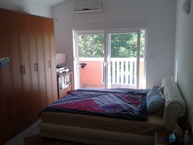 Schlafzimmer in einer Wohnung in Igalo, Montenegro: Doppelbett, großer Kleiderschrank, Klimaanlage und Zugang zum Balkon.
