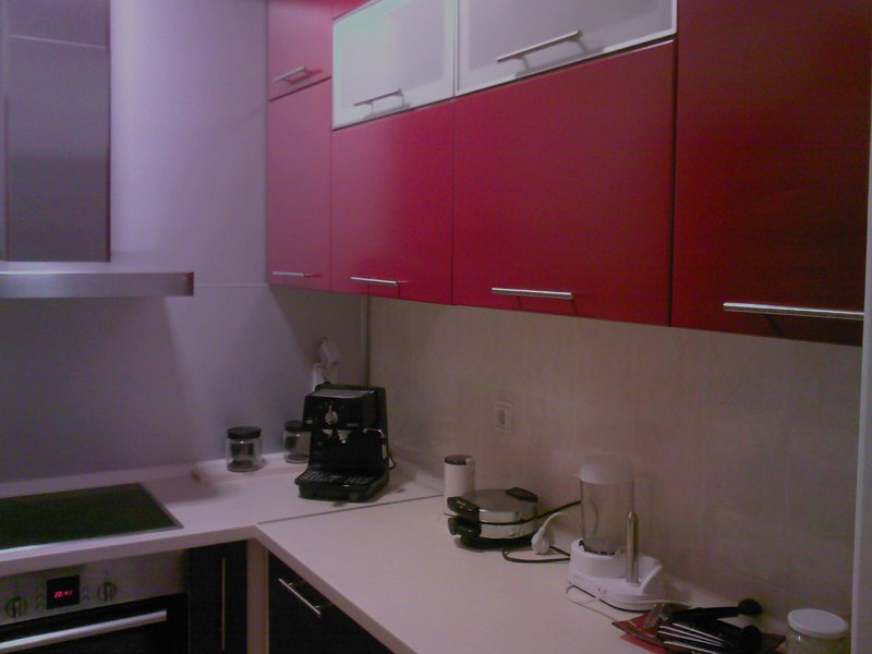 Moderne Küche mit roten Fronten und Einbaugeräten in einer zum Verkauf stehenden Wohnung, Stadt Budva, Montenegro.