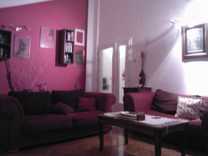Gemütliches Wohnzimmer mit bordeauxfarbenen Sofas und einer farbigen Wand in einer zum Verkauf stehenden Wohnung in Budva, Montenegro.