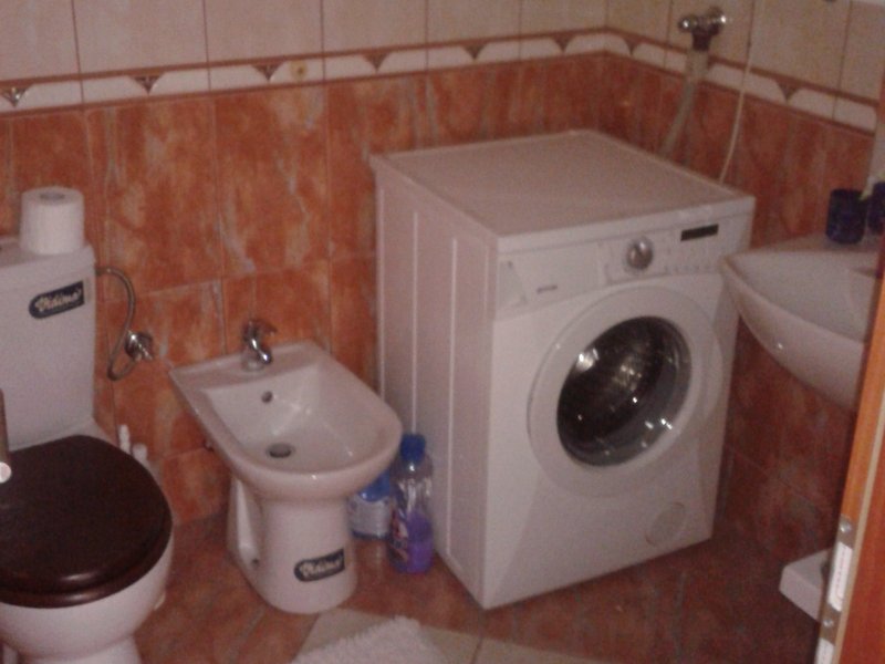 Badezimmer in einer Wohnung in Igalo, Montenegro: Fliesen, Toilette, Bidet und Waschmaschine im Innenraum.